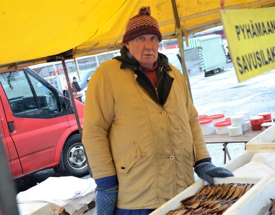 65-årig torgförsäljare står bakom sitt fiskstånd.