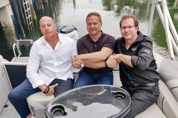 tre män sitter i en båt och skakar hand