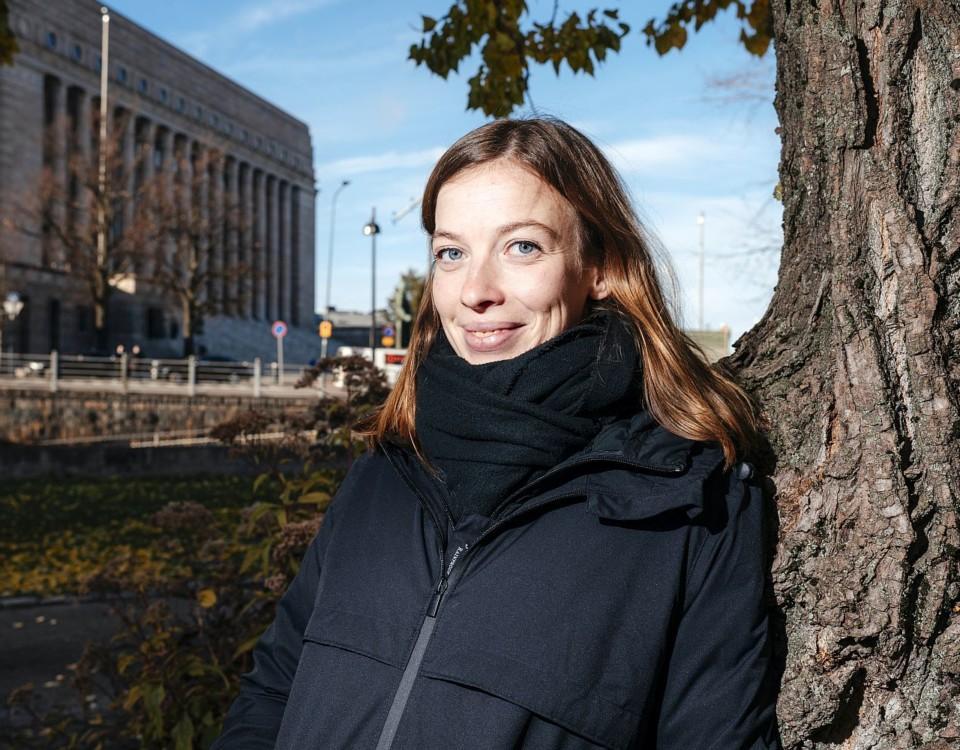 Kvinna lutar mot träd vid vid riksdagshuset i Helsingfors