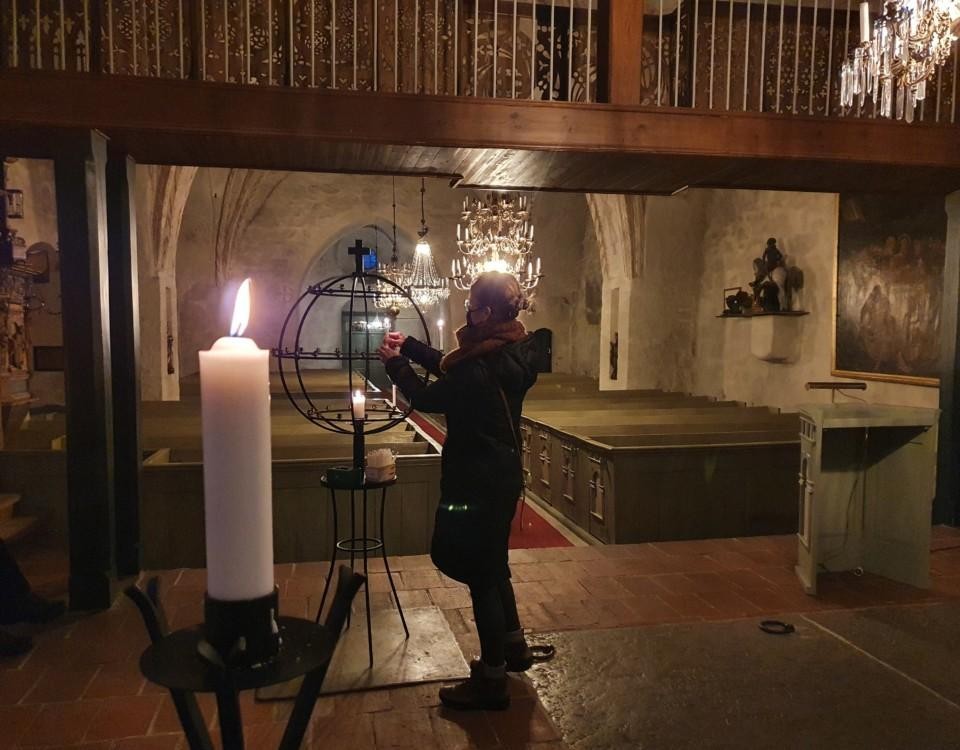 En kvinna tänder ett ljus i en kyrka.