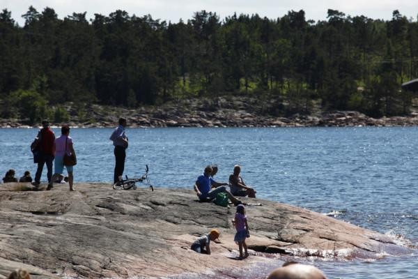 Folk på en klippa vid vattnet en solig dag.