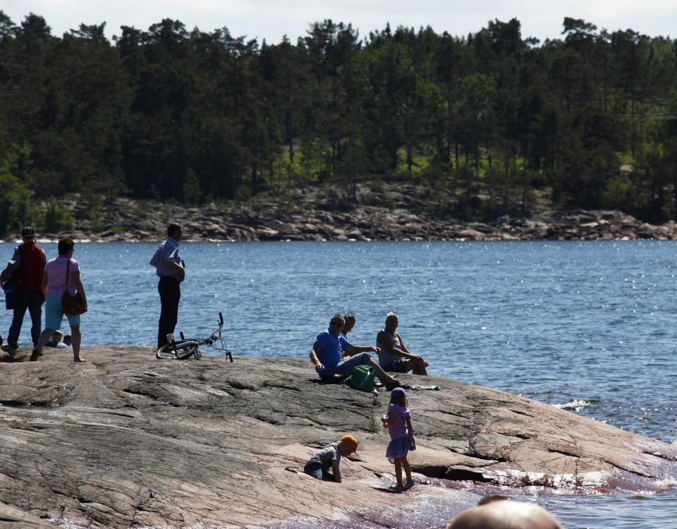 Folk på en klippa vid vattnet en solig dag.