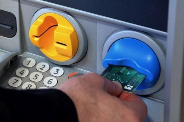 En hand säter in en bankkort i en bankomat
