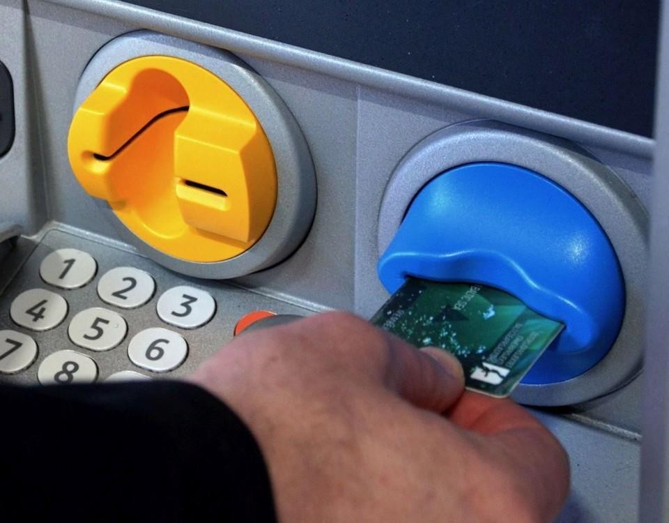En hand säter in en bankkort i en bankomat
