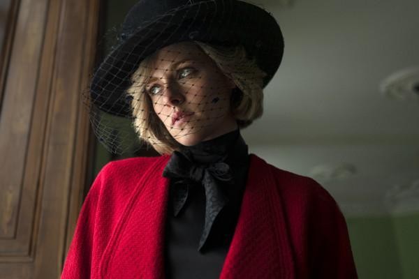 en kvinna i röd jacka med svart hatt som har nät för ansiktet