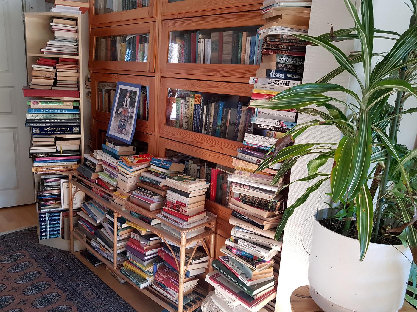 bokhylla fylld med böcker och bokhögar invid