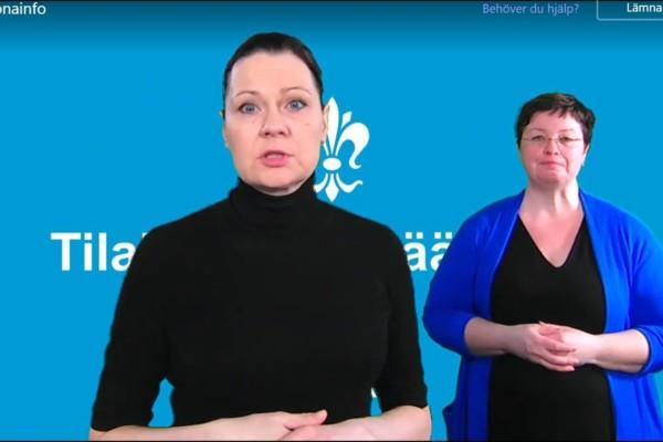 kvinna i svart tröja mot blå bakgrund, annan kvinna i blå tröja i bakgrunden