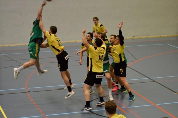 Handbollsspelare i gula och gröna spelskjortor mitt i en match