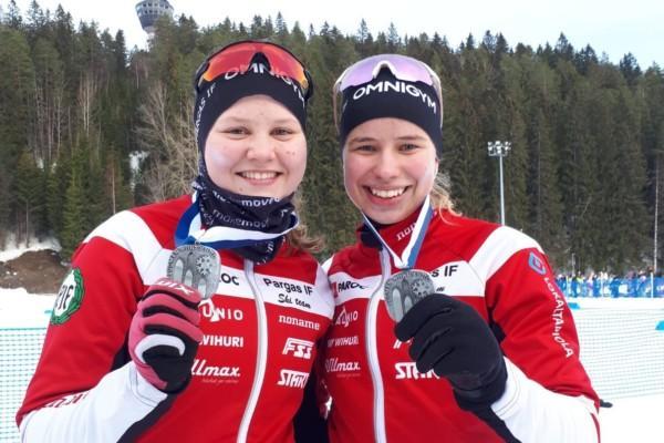 Två kvinnliga skidåkare med medaljer.