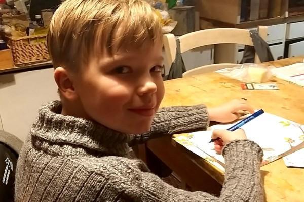 pojke skriver brev vid ett köksbord