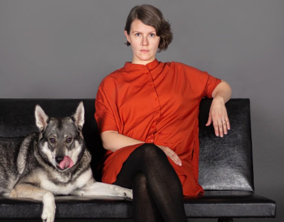 En kvinna sitter på en soffa med en hund.