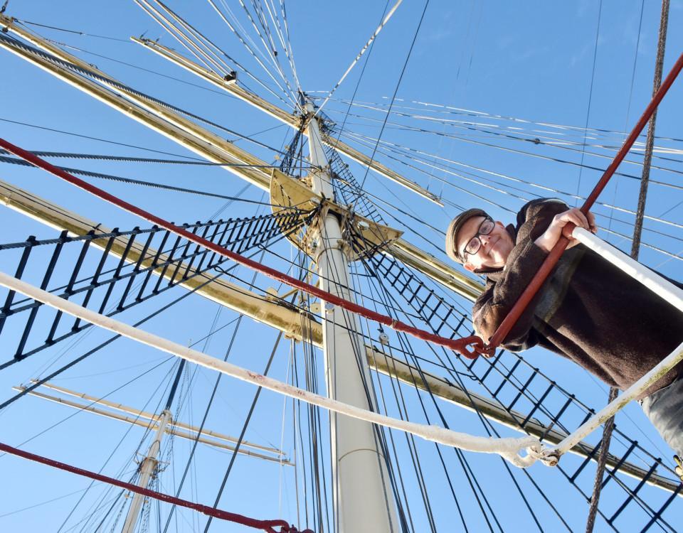 en man i en mast på ett segelfartyg