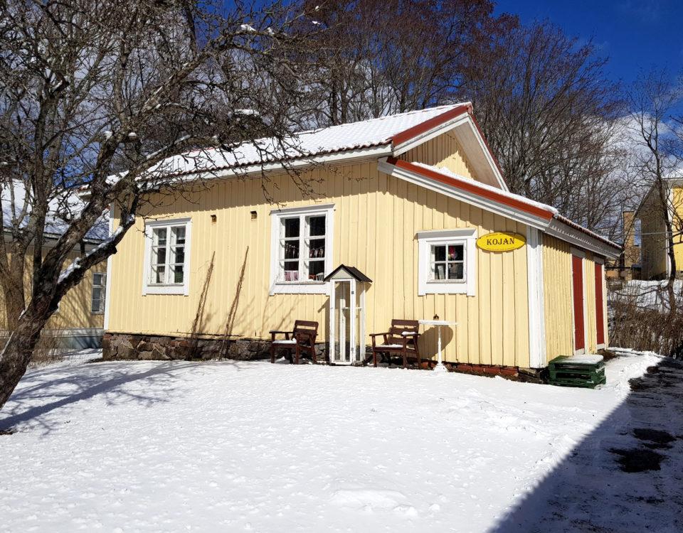 Litet gult hus i vinterlandskap