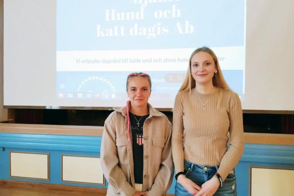 Två flickor framför en presentation med titeln "Mjauff Hand- och katt dagis Ab