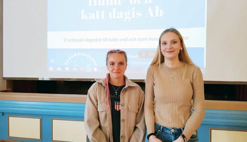 Två flickor framför en presentation med titeln "Mjauff Hand- och katt dagis Ab