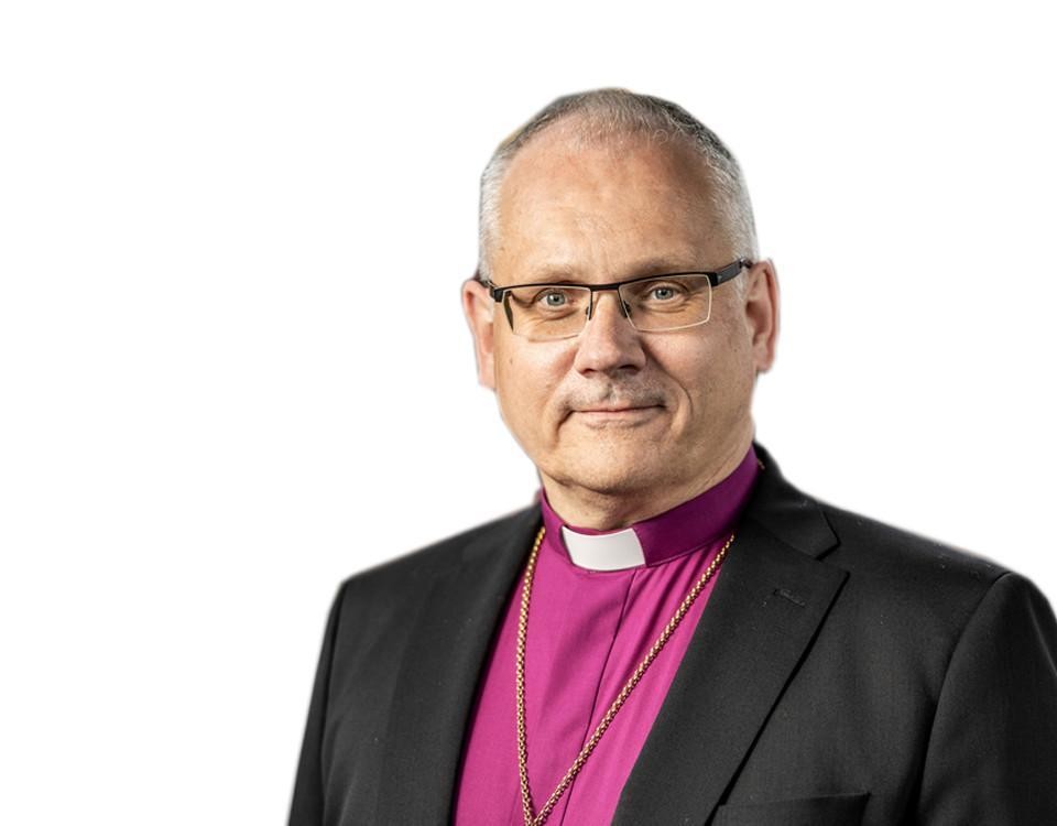 manlig biskop med lila skjorta, prästkrage och mörk kavaj