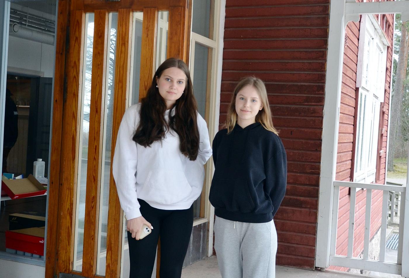 två tjejer står vid en ytterdörr