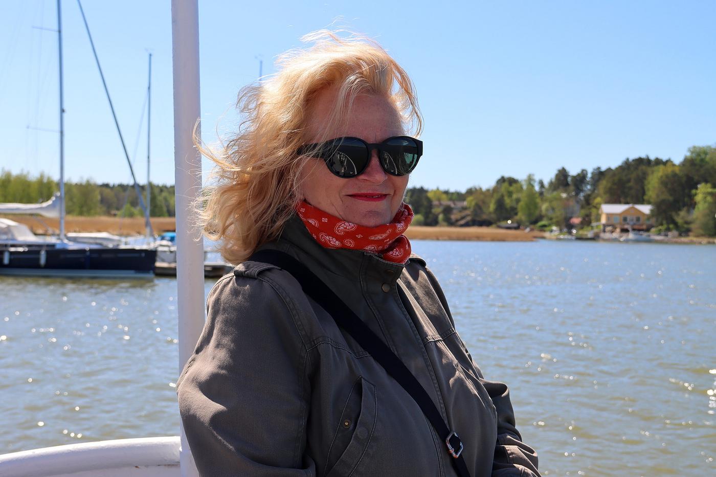 En kvinna med solglasögon i fören av en båt.