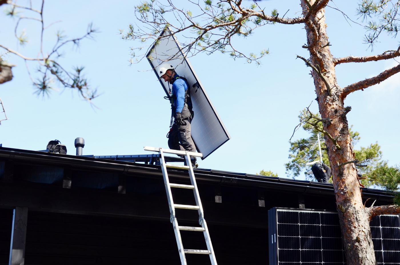 en man står på ett tak med en solpanel på ryggen