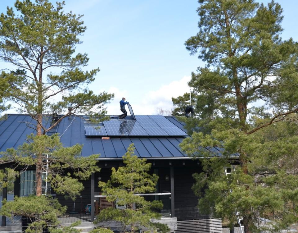 en man installerar solpaneler på ett tak