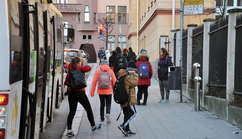 Barn stiger av buss vid hållplats i stadsmiljö
