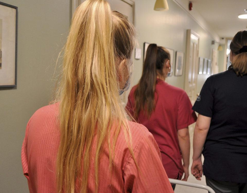 tre vårdare fotade bakifrån i en korridor
