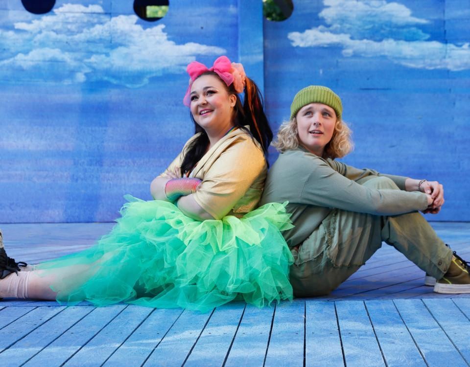 två skådespelare sitter med ryggen mot varandra, ur pjäsen om Peter Pan