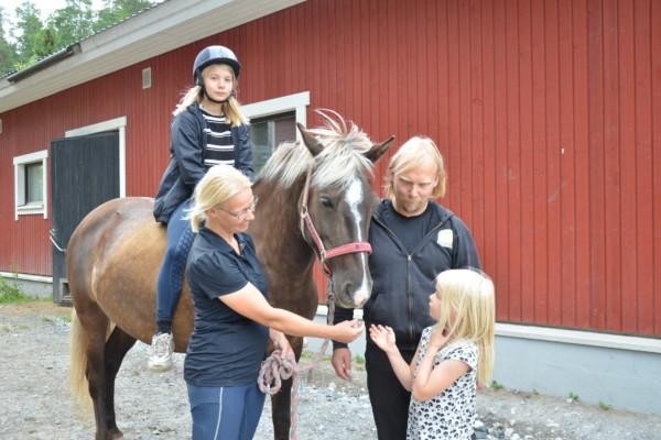 två barn och två vuxna med en häst