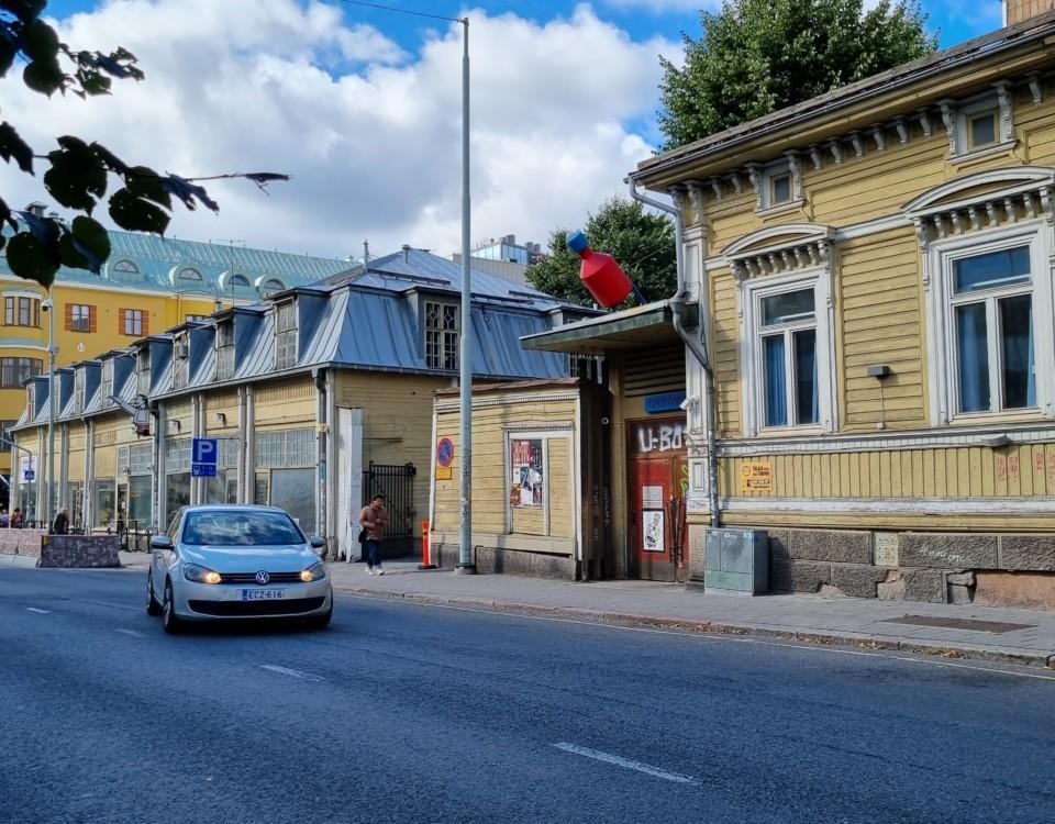 gatuvy med gult gammalt och slitet höghus till höger