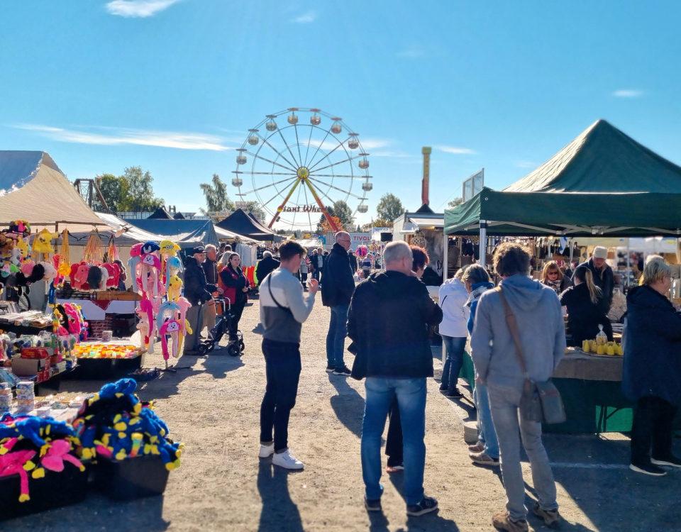 Folk på höstmarknad i Ekenäs. Pariserhjul i bakgrunden.