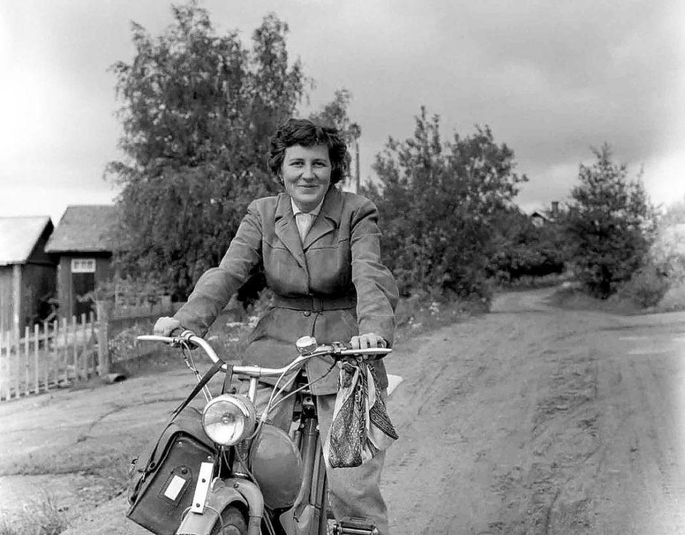 Ett svartvitt foto på en kvinna på moped.