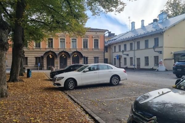 Gamla stadshus med bilar framför, gula löv på marken