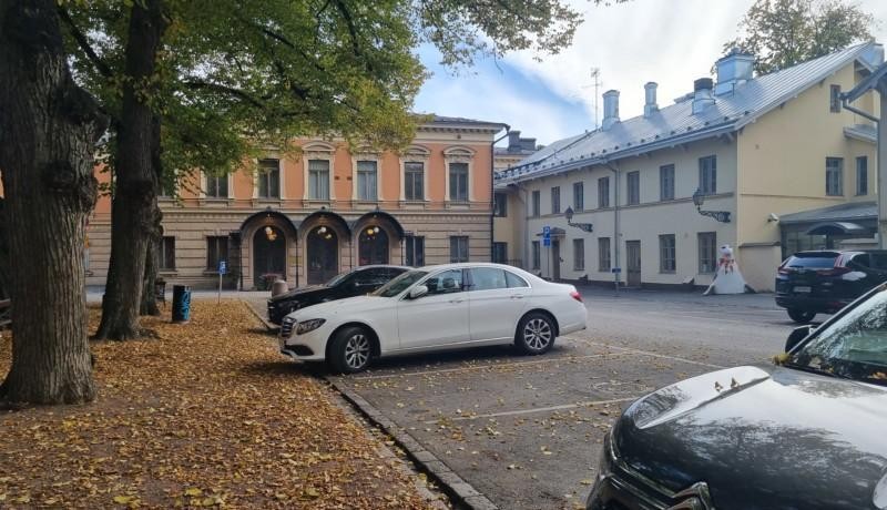 Gamla stadshus med bilar framför, gula löv på marken