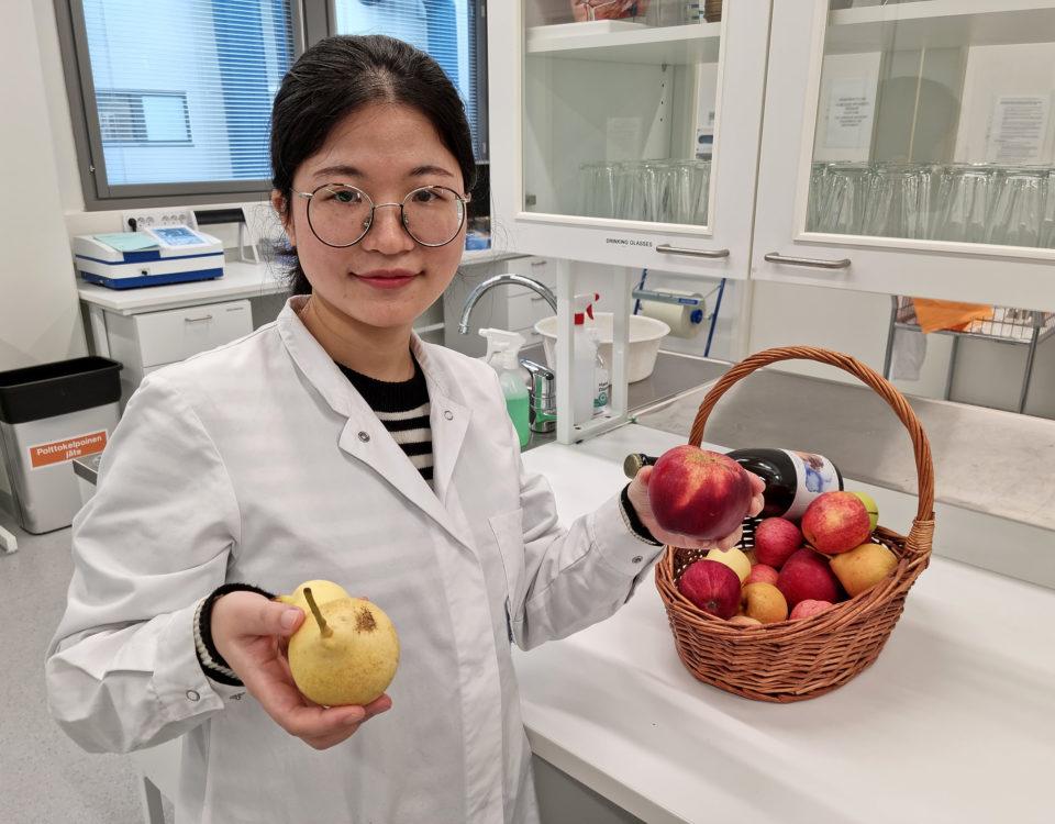 Kvinna i laboratorium med en korg äpplen.