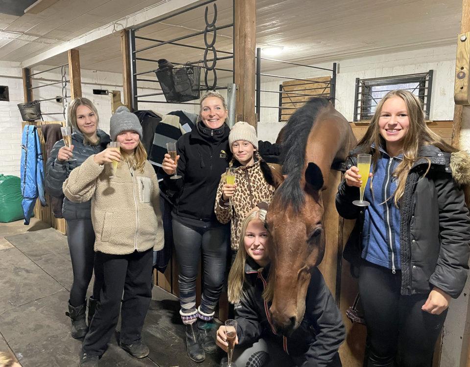 Sex personer och en häst i ett stall