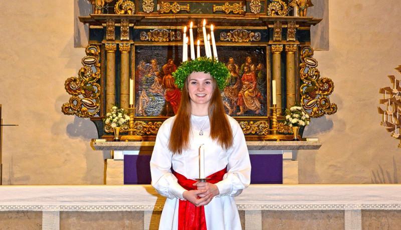 Luciaklädd kvinna framför altare