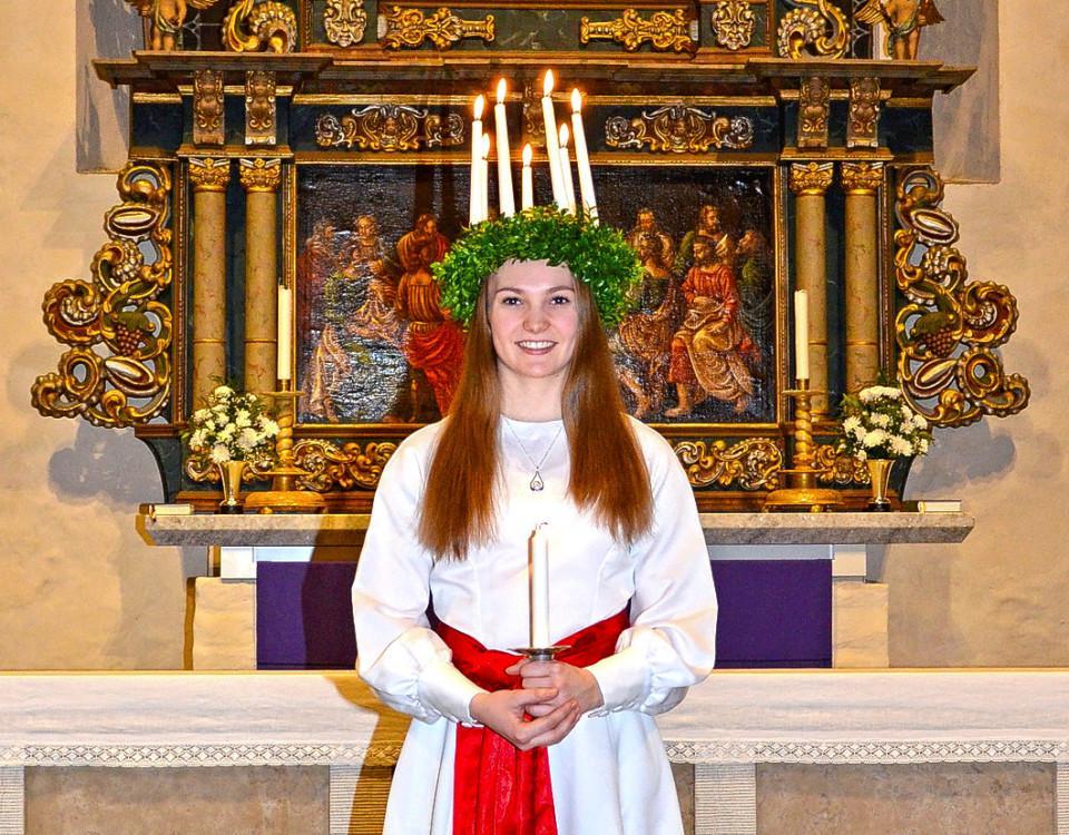 Luciaklädd kvinna framför altare