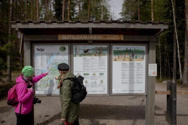 Två personer pekar på en informationsskylt i en skog