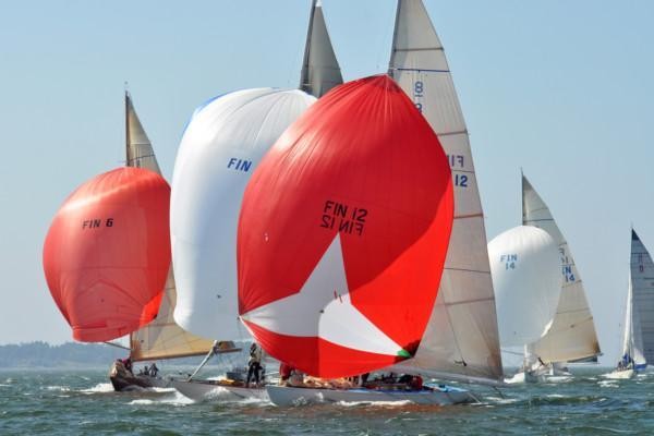 Segelbåtar med stora, buktande segel i rött och vitt
