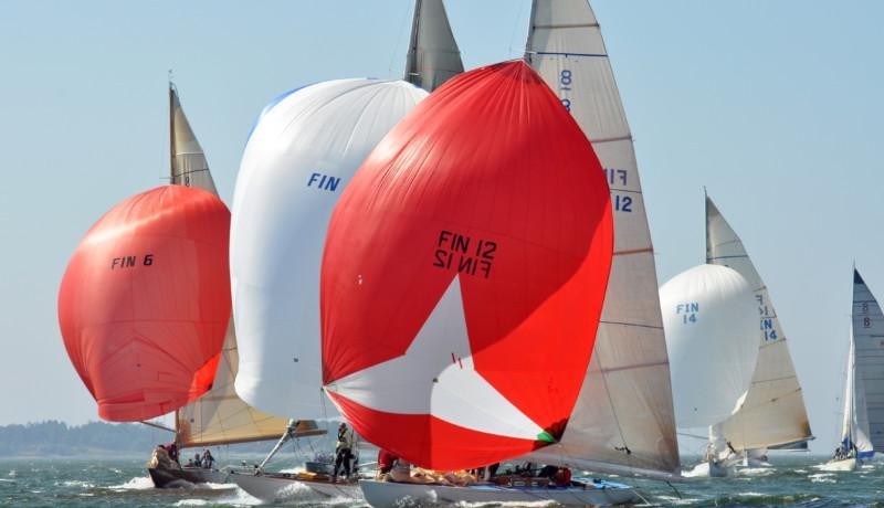 Segelbåtar med stora, buktande segel i rött och vitt