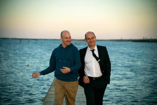 Två män står bredvid varandra med hav i bakgrunden