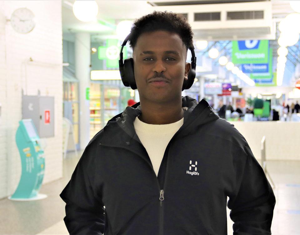 En ung man med hörlurar för öronen i ett köpcenter.