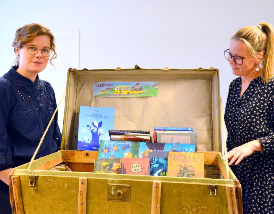två kvinnor med en öppen resväska med böcker i
