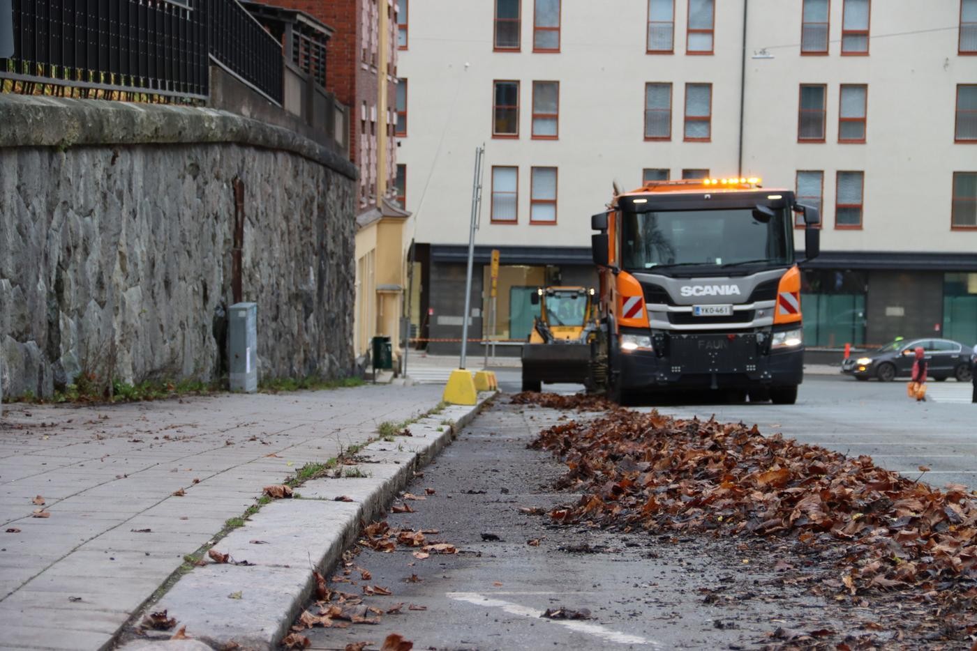 En sopbil som putsar en gata ren från löv.