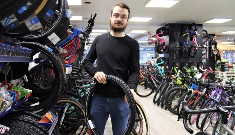 En man håller upp en cykelring i en affär.