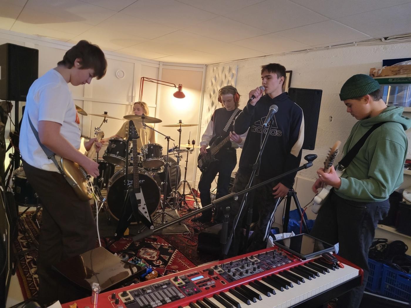 Fem unga killar spelar musik i en studio.