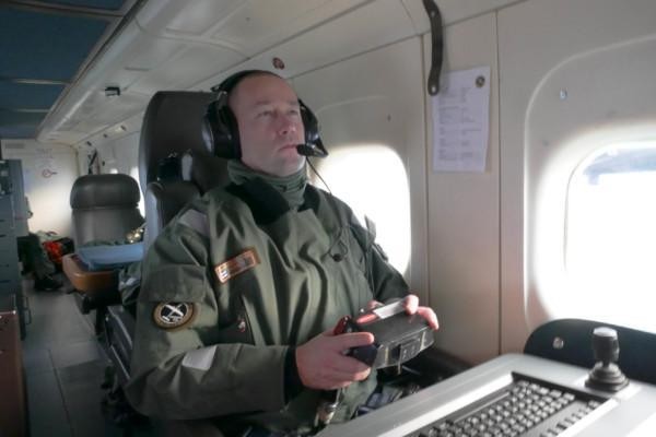 En gränsbevakare sitter i ett flygplan och tittar på en skärm