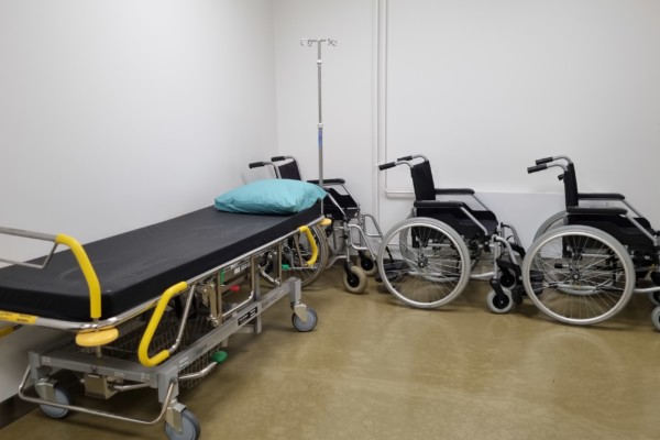 en sjukhusbrits och två rullstolar i ett väntrum