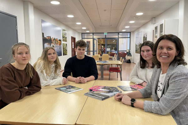 fyra ungdomar och en dam vid ett bord i en skolkorridor