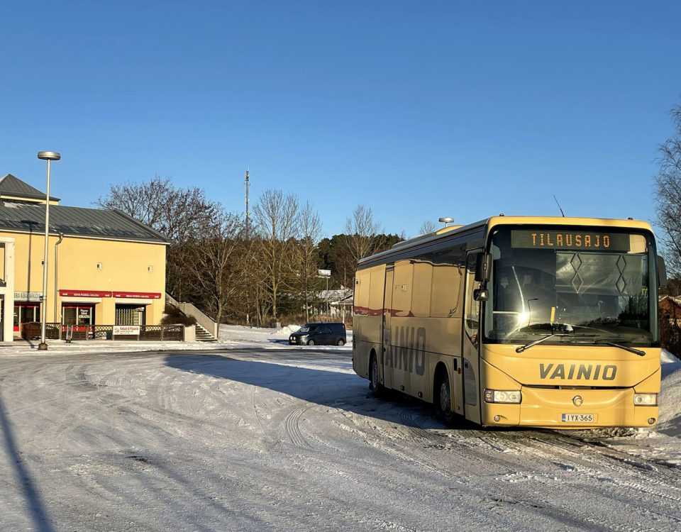 En gul Vainio-buss på en snötäckt plan.